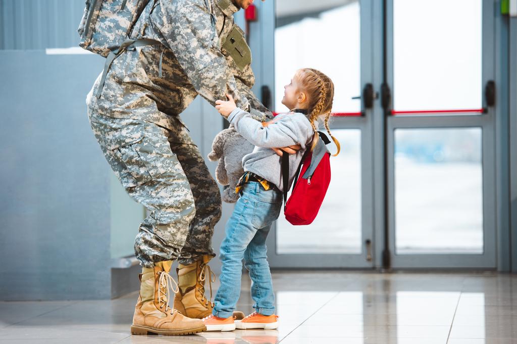 happy daughter holding father in military uniform in airport  - Photo, Image