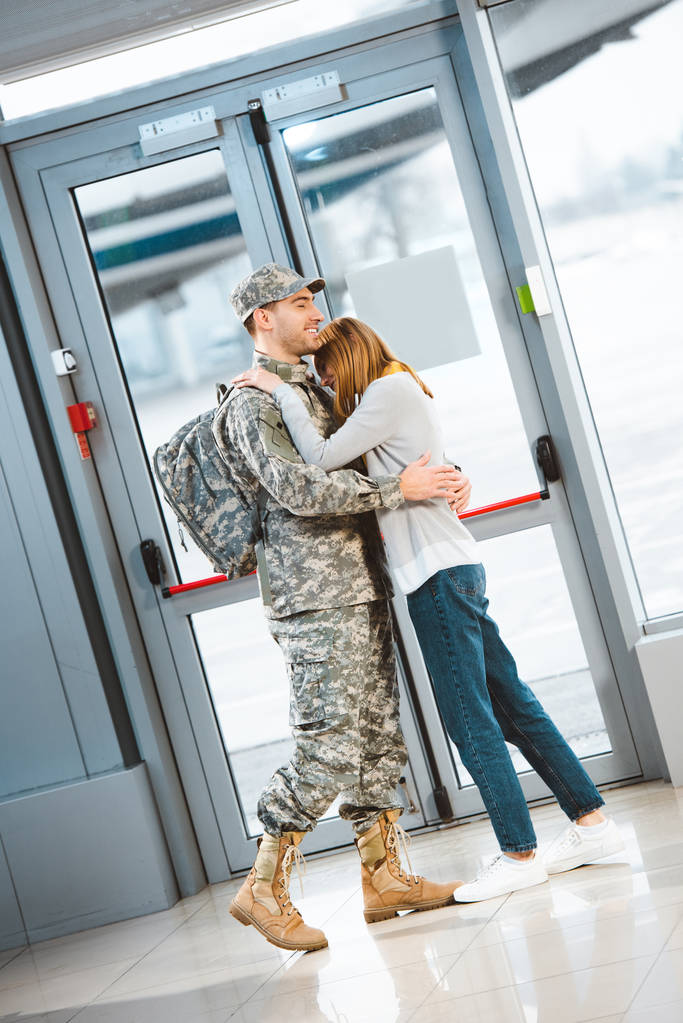 空港で軍服を着て幸せ彼女抱き笑顔彼氏 ロイヤリティフリー写真 画像素材