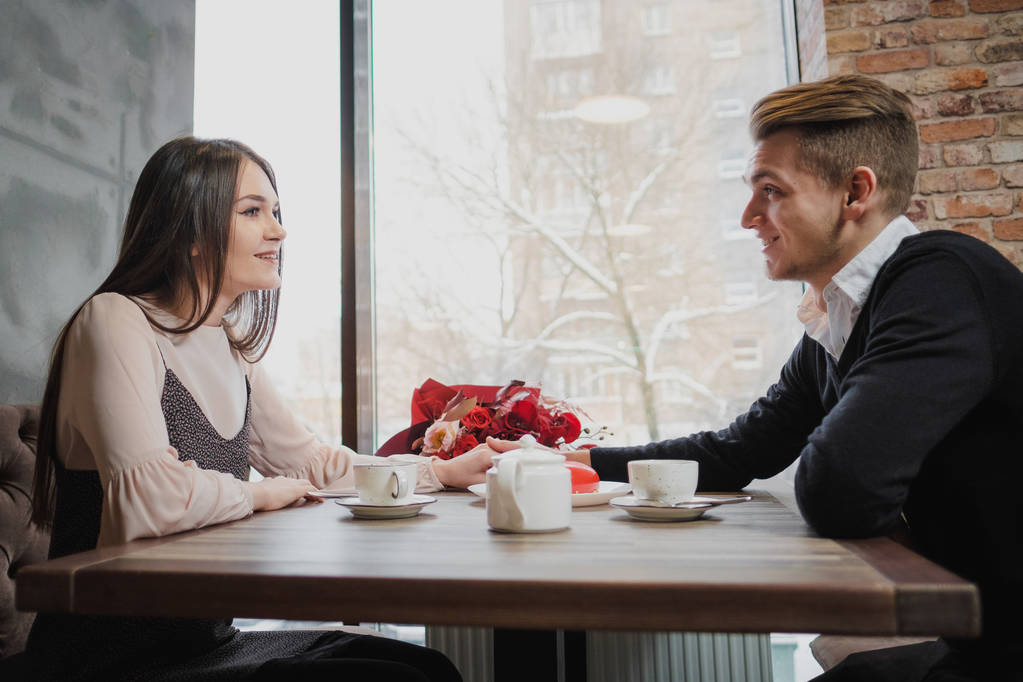 junges verliebtes Paar, Mann und Frau, sitzen an einem Tisch in einem Café. Valentinstag. - Foto, Bild