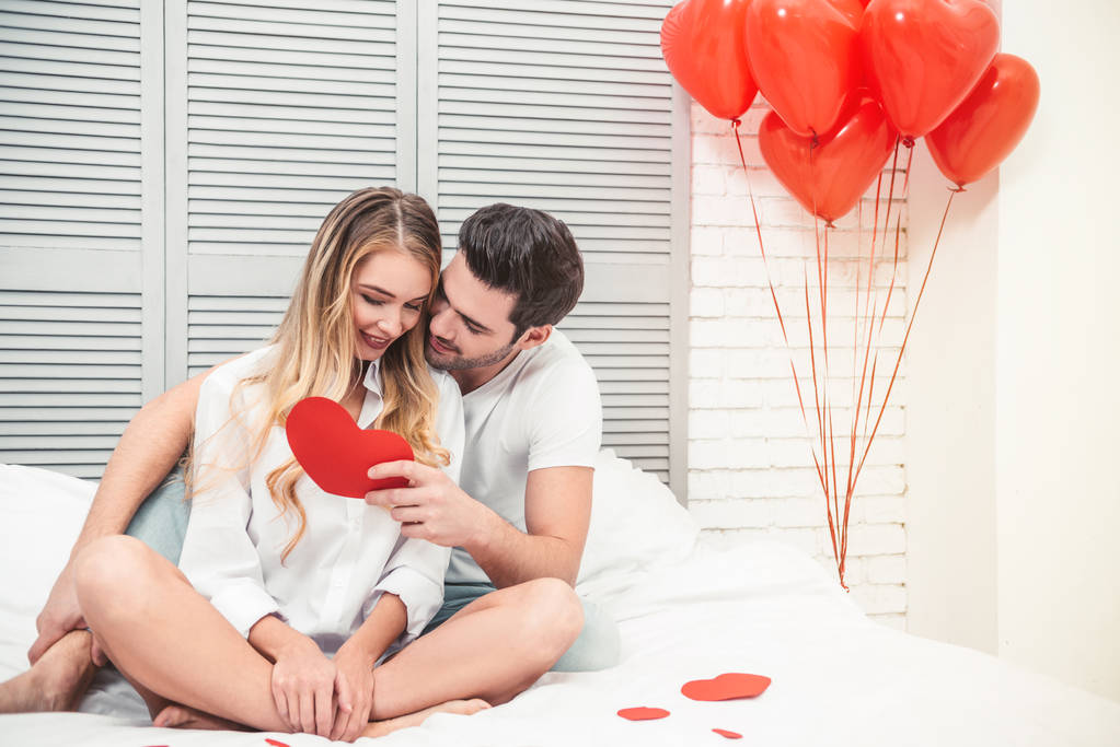 handsome man with girlfriend reading gift card in the heart shape at valentines day - Φωτογραφία, εικόνα