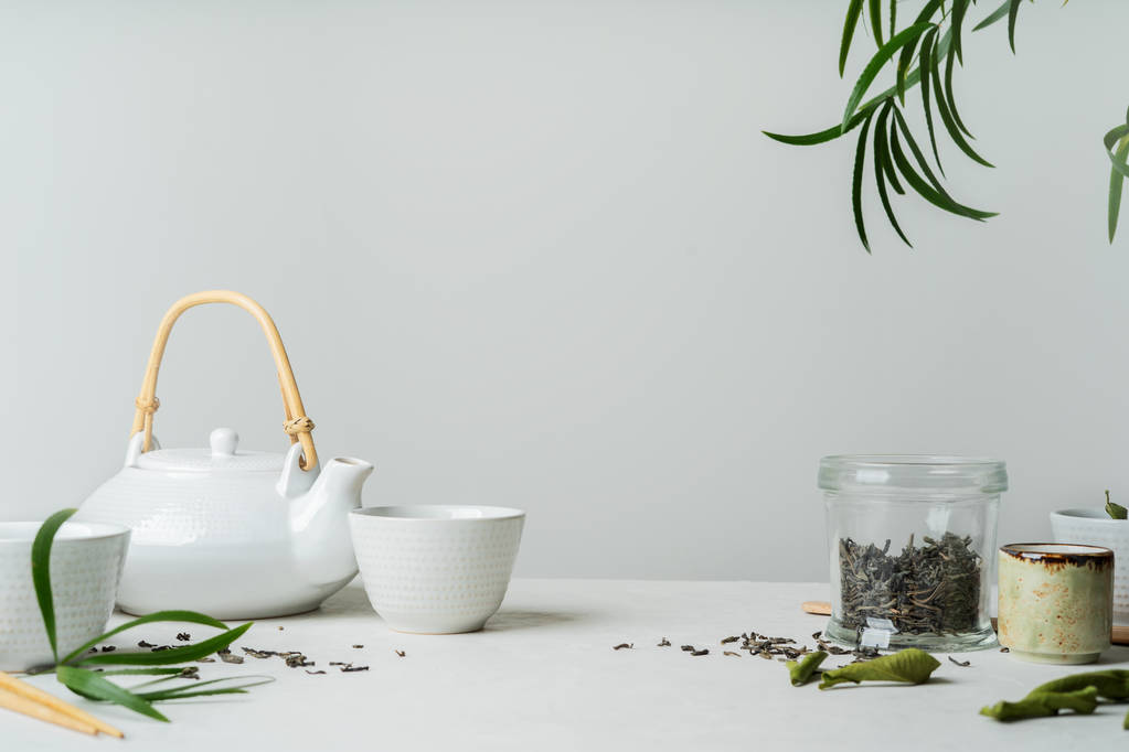 Asya çay kavramı, iki beyaz bardak çay ve yeşil çay kuru ile çevrili çaydanlık yaprakları, beyaz arka plan üzerinde bir metin için yer. Bira ve çay içme. - Fotoğraf, Görsel