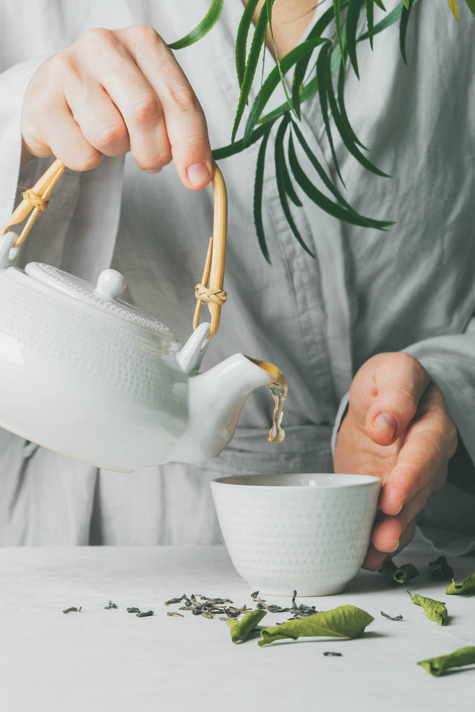 女性は、ティーポットからティーカップ セレクティブ フォーカスにお茶を注いだを手します。醸造とお茶を飲む. - 写真・画像