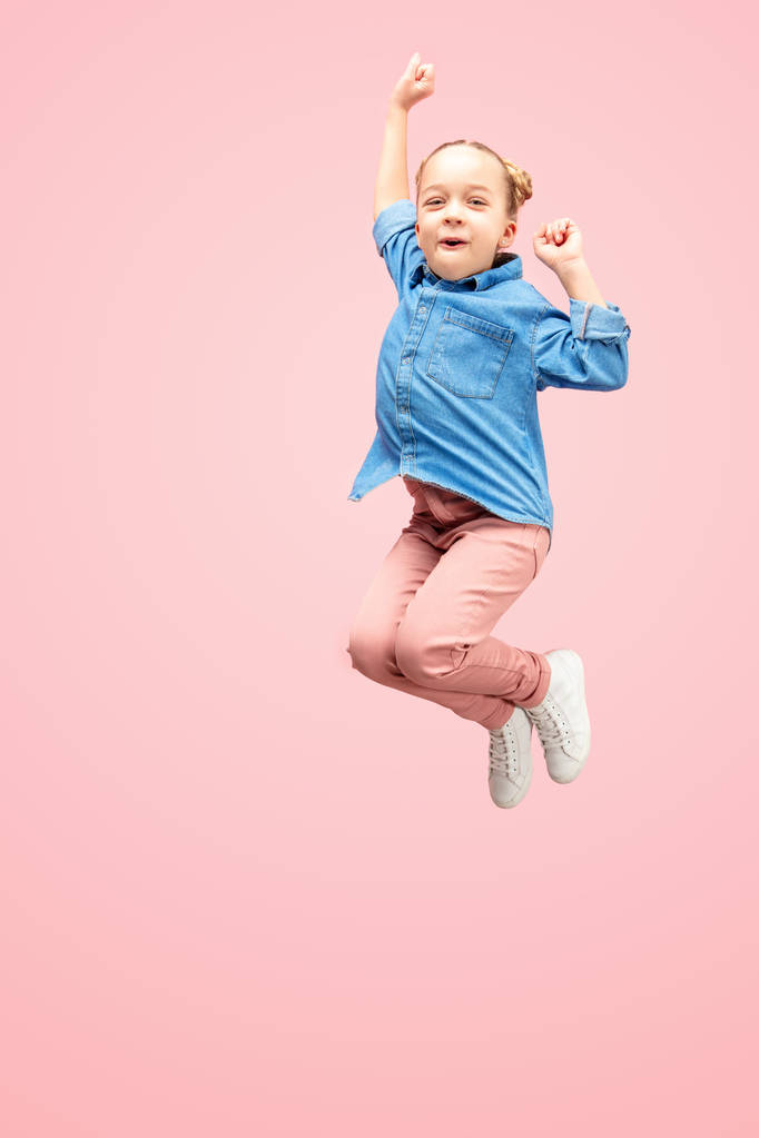Gelukkig Kaukasische tiener meisje springen in de lucht, geïsoleerd op roze studio achtergrond. - Foto, afbeelding