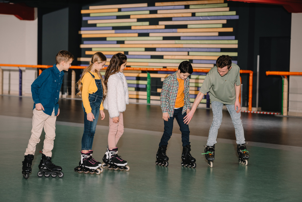Instrucción joven explicando los métodos de patinaje a los niños
 - Foto, imagen