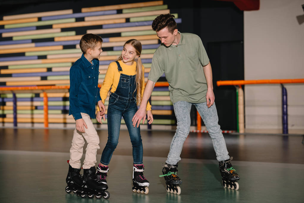 Young trainer explaining skating technics to attentive children - Photo, Image