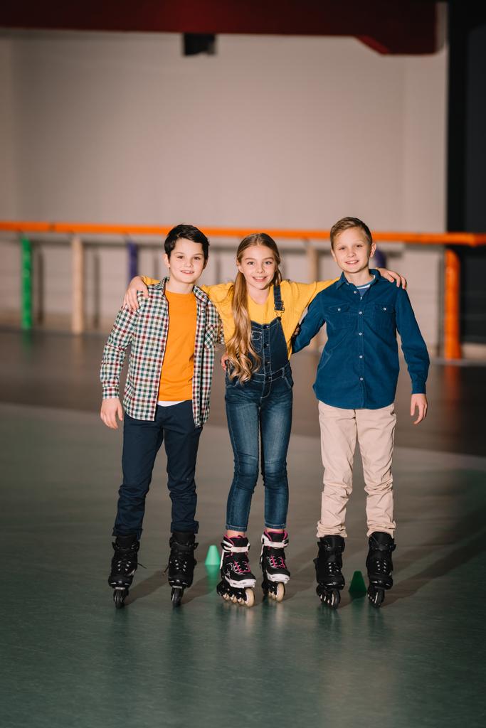 Tiro de comprimento total de sorrir abraços de crianças na pista de patinação
 - Foto, Imagem