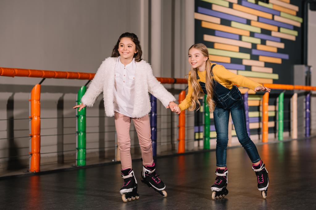 かわいい姉妹がローラー スケート場でスケートをしながら手を繋いで - 写真・画像
