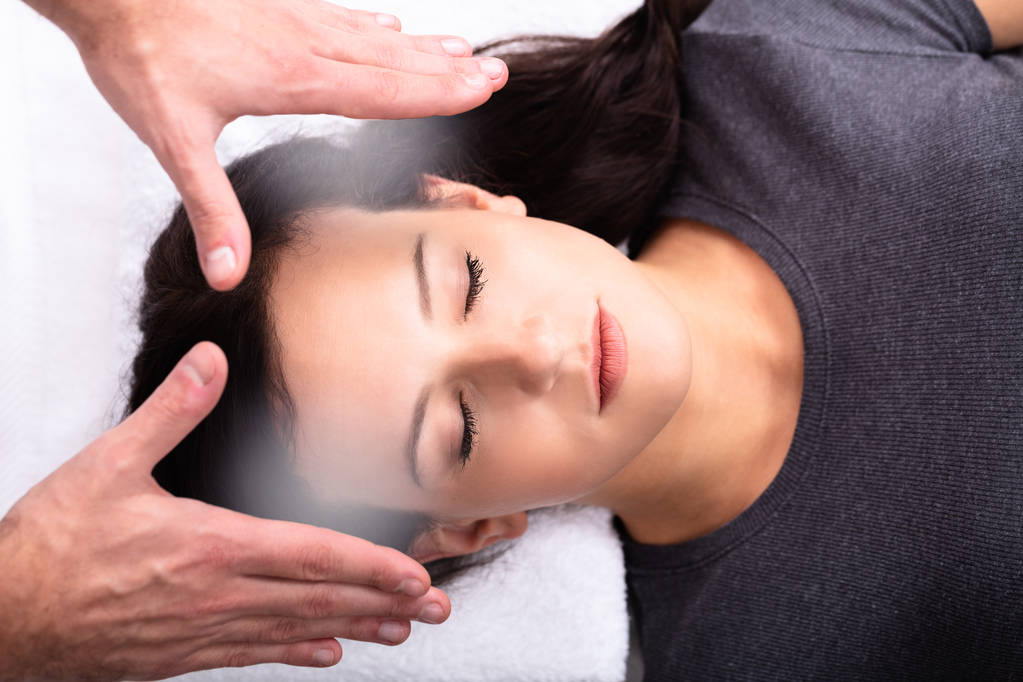 Primer plano de una mano terapeuta dando tratamiento de curación Reiki a la mujer en el spa
 - Foto, imagen