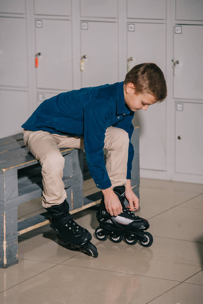 Niño de camisa azul poniéndose patines negros
 - Foto, Imagen