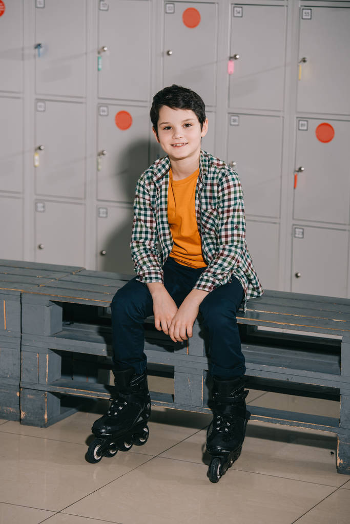 Mignon garçon brune en chemise à carreaux posant en patins à roulettes
 - Photo, image