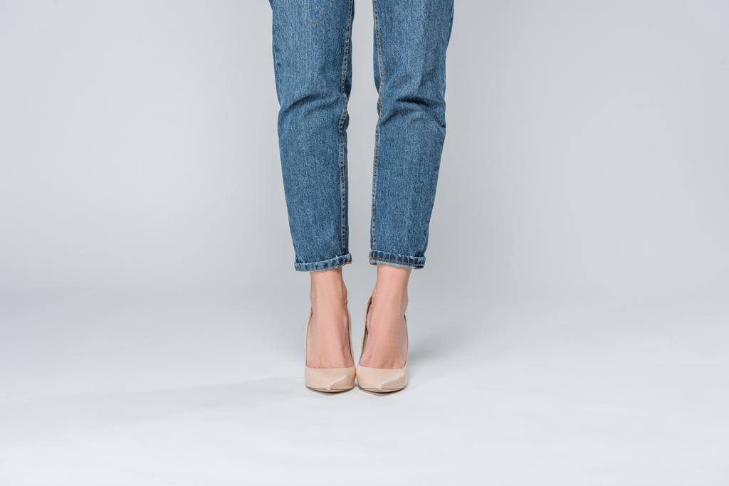 низкий вид секции девушки в джинсах и на высоких каблуках, изолированных на сером
  - Фото, изображение