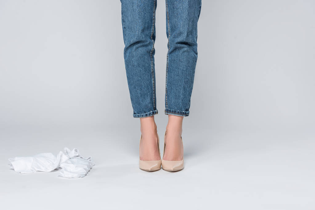 обрезанный вид женщины в джинсах и на высоких каблуках раздетой изолированной на сером
  - Фото, изображение
