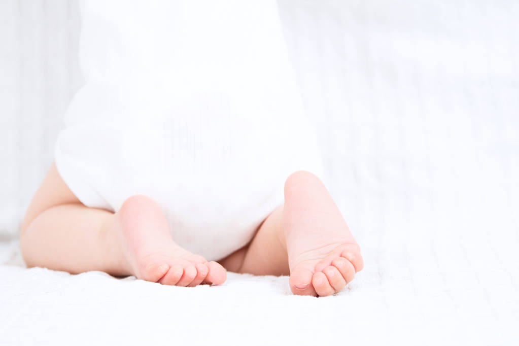 Sección baja del bebé de pie sobre fondo blanco. Pie de bebé
. - Foto, imagen