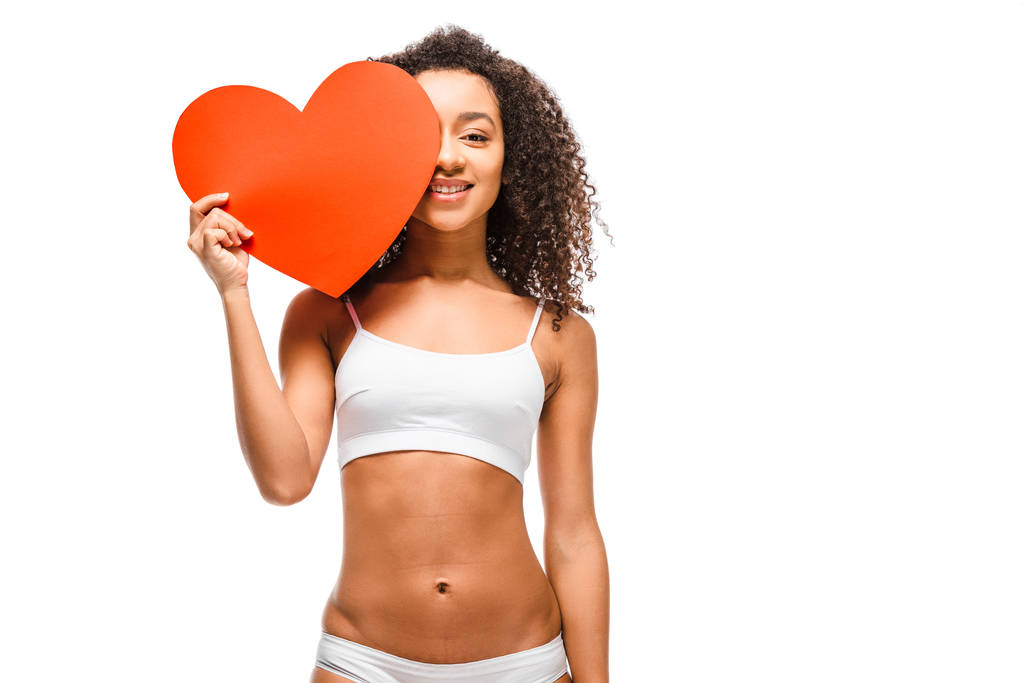 beautiful african american girl in underwear posing and holding heart shaped card isolated on white - Photo, Image