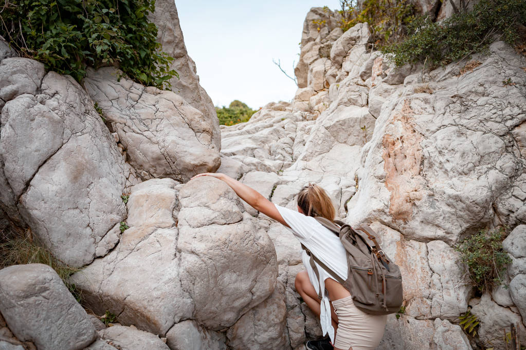 Hiker woman on hiking trail climbing on mountain among rocks, travel and active lifestyle concept - Photo, Image