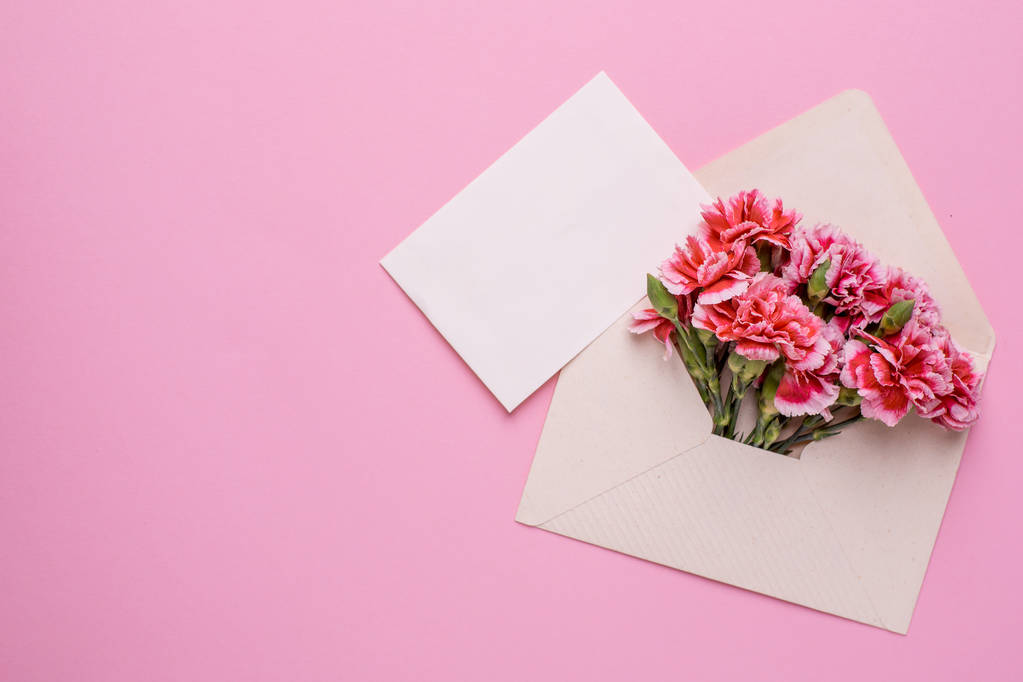 Koperta z różowymi kwiatami i kartka prezentowa na różowym tle widok z góry - Zdjęcie, obraz