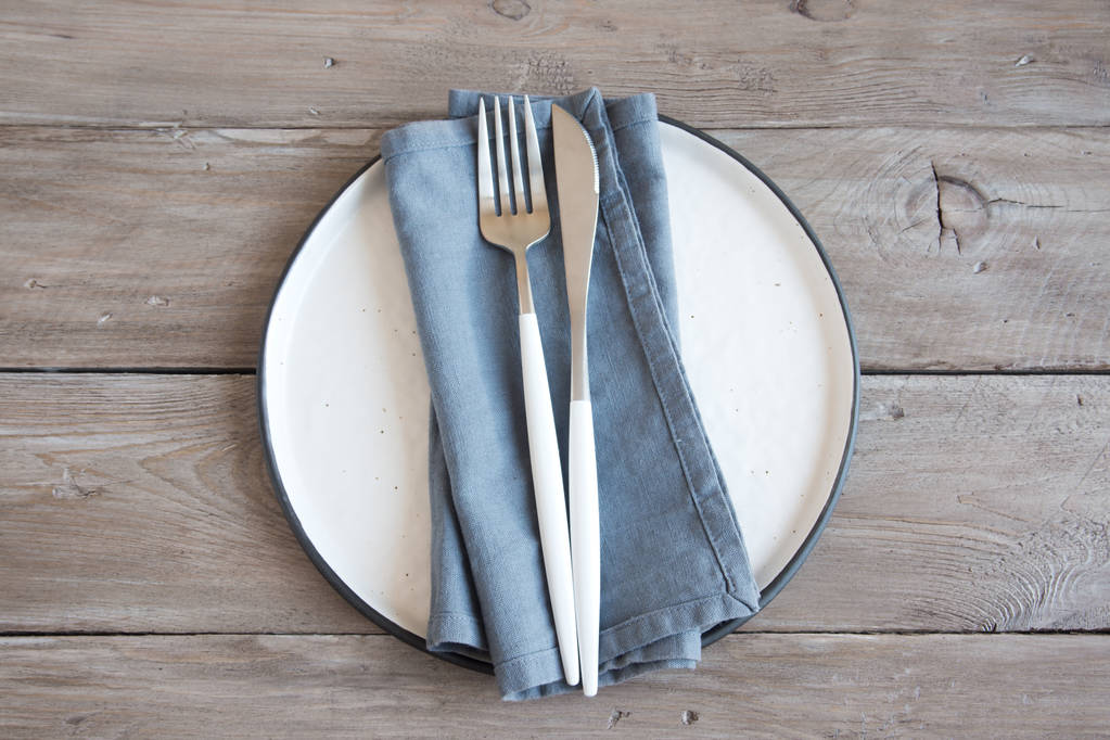 Natural table setting - plain ceramic plate, linen napkin, cutlery on wooden table. Eco-friendly concept, nordic style. - Photo, Image