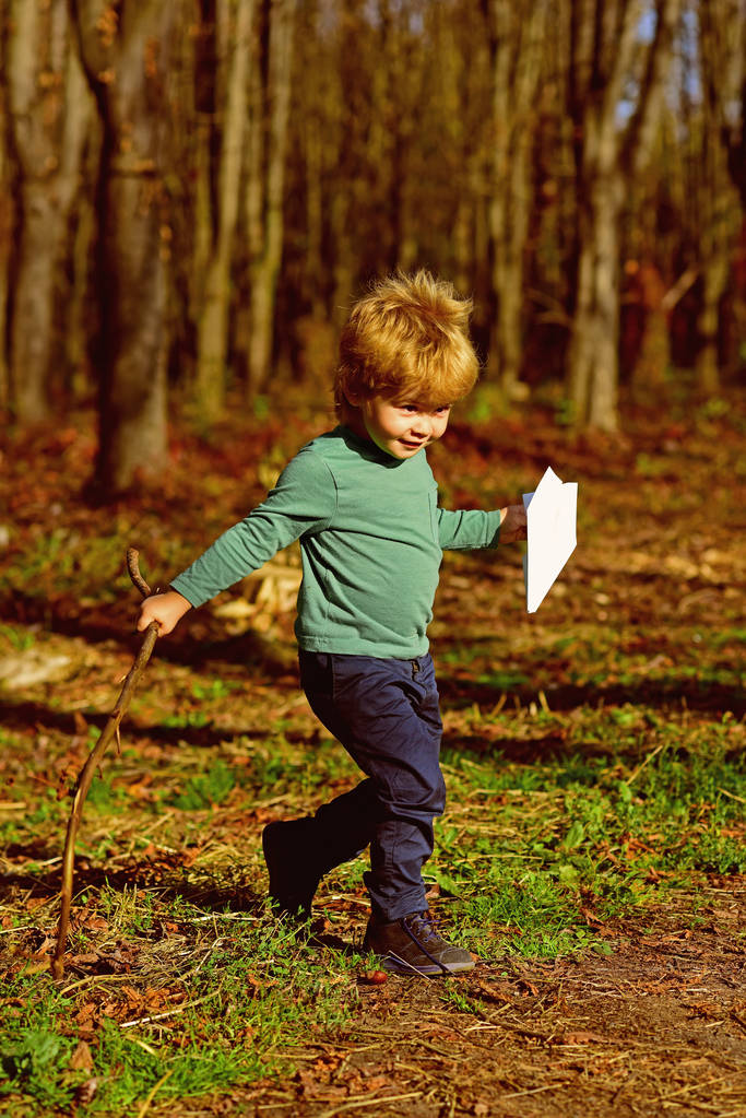 Маленький мальчик запускает бумажный самолет игрушку на открытом воздухе. Маленький ребенок играет с игрушкой в парке. Время на отдых, поезжайте на самолете
 - Фото, изображение