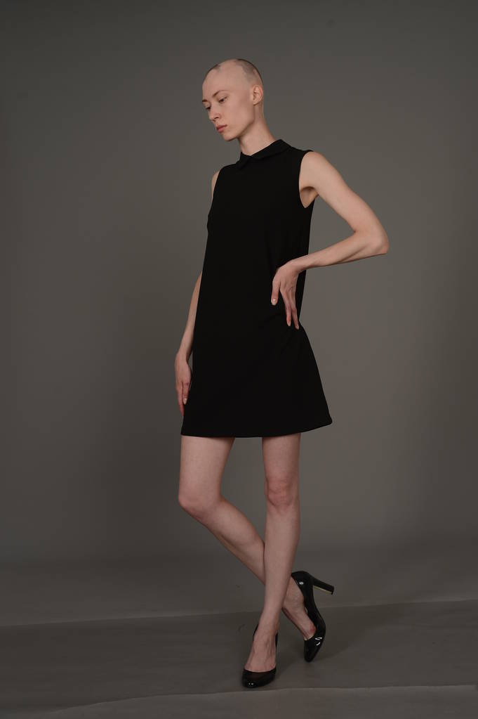 лысая девушка позирует в студии в черном платье
 - Фото, изображение