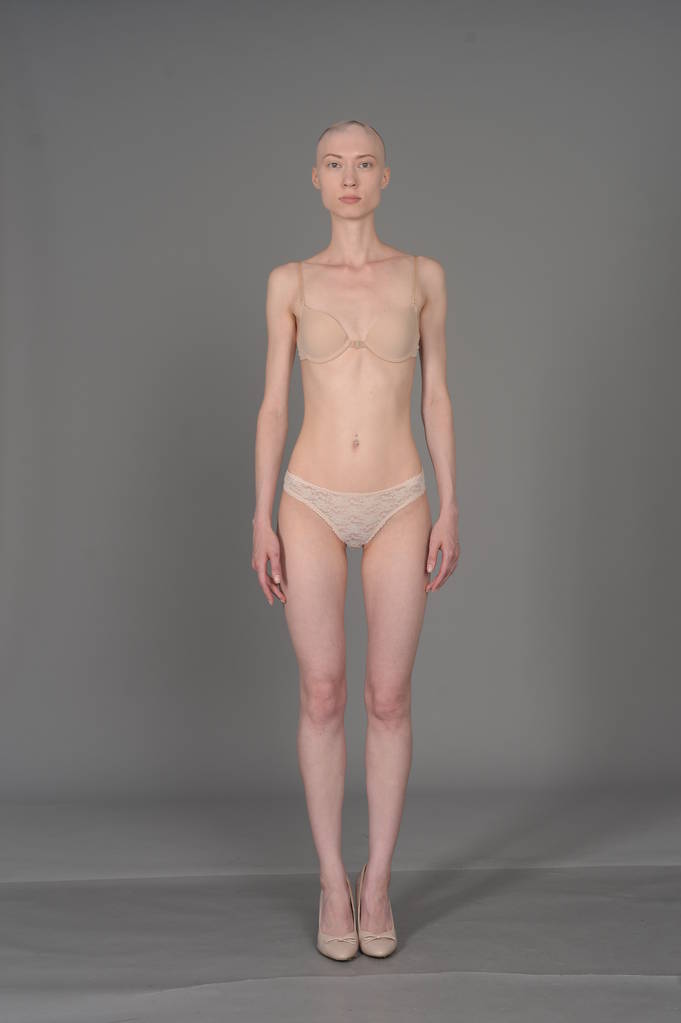 kalju tyttö beige alusvaatteet poseeraa harmaalla taustalla
 - Valokuva, kuva