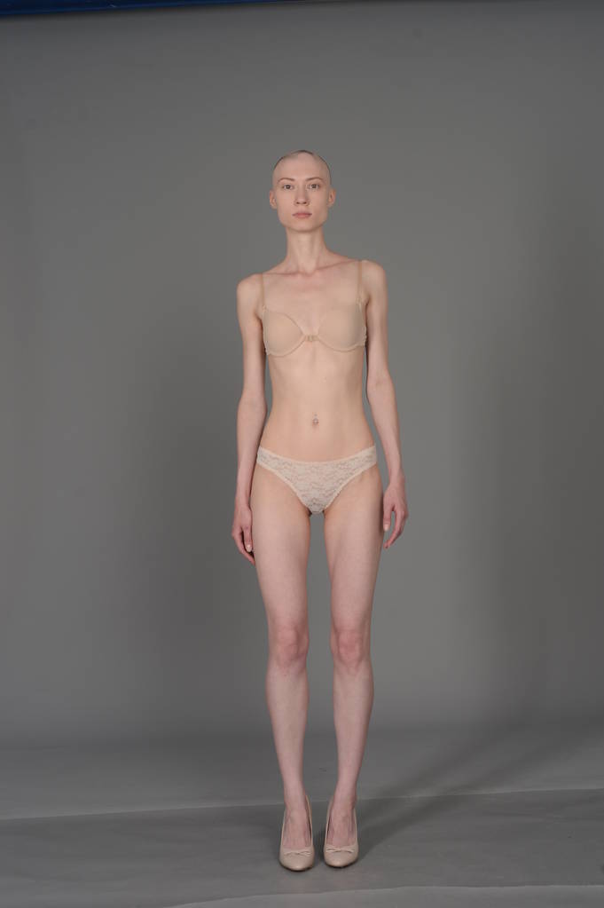 careca menina em lingerie bege posando no fundo cinza
 - Foto, Imagem