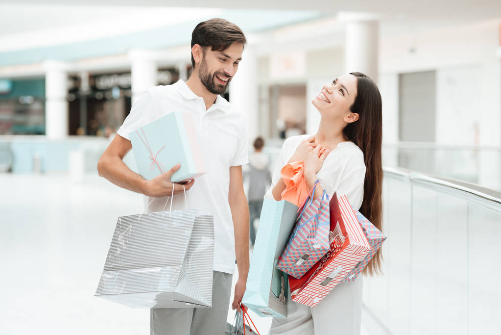 Mies ja nainen kävelevät toiseen kauppaan ostoskeskuksessa. Pari on onnellinen.
. - Valokuva, kuva