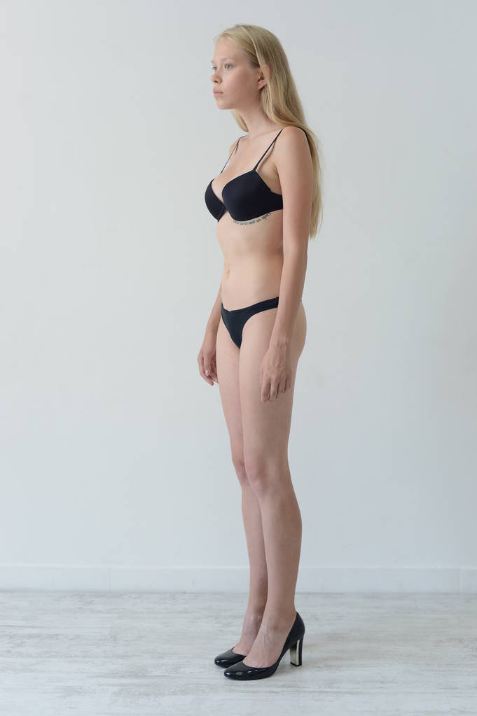 modelo prueba chica en lencería negra con tatuaje posando en Studio sobre fondo gris
 - Foto, Imagen