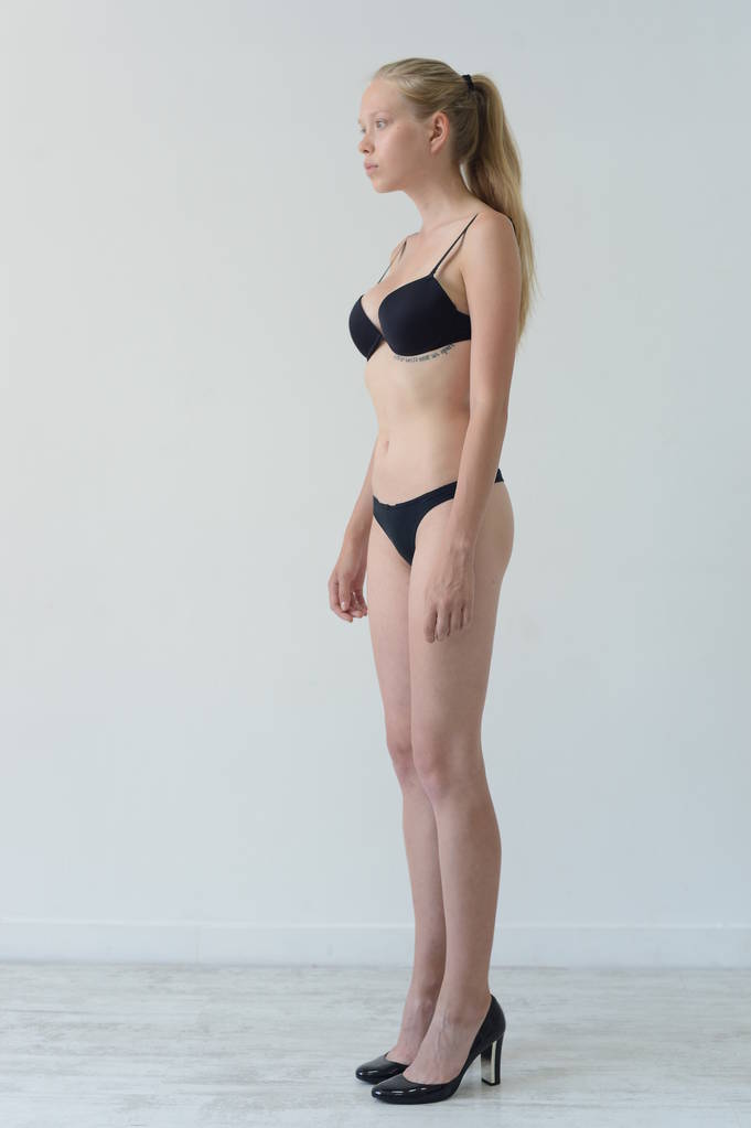 Model testy dziewczyna w czarnej bieliźnie z tatuaż pozowanie w Studio na szarym tle - Zdjęcie, obraz