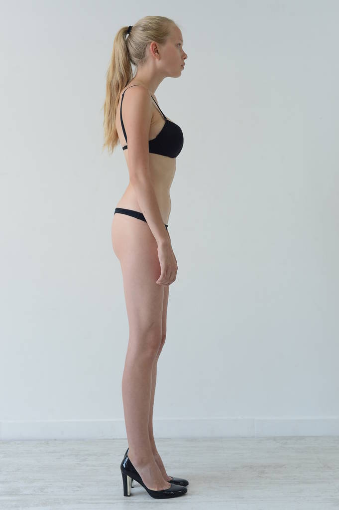 model tests meisje in zwarte lingerie met tattoo poseren in Studio op grijze achtergrond - Foto, afbeelding