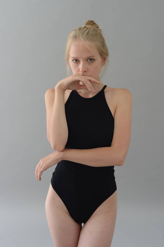 девушка в черном купальнике с белыми волосами позирует в студии на сером фоне
 - Фото, изображение