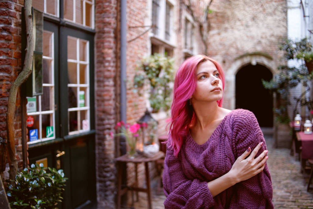 Una chica joven y hermosa con el pelo rosa camina por el viejo patio de piedra. Colores creativos
 - Foto, Imagen