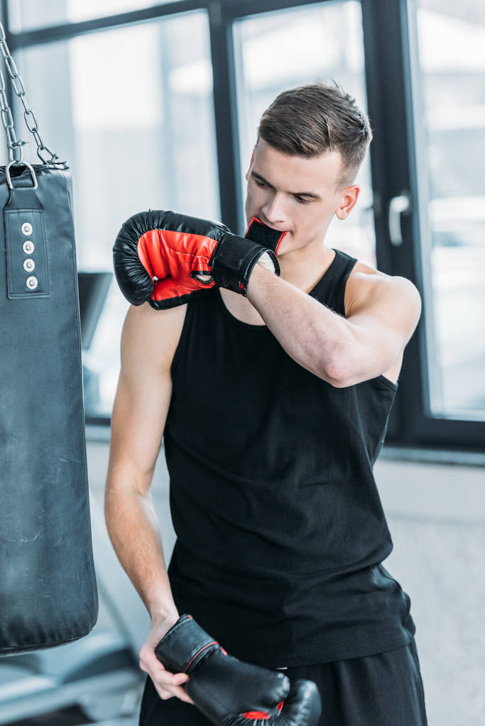 urheilullinen nuori urheilija yllään nyrkkeily käsine hampaat kuntosalilla
 - Valokuva, kuva
