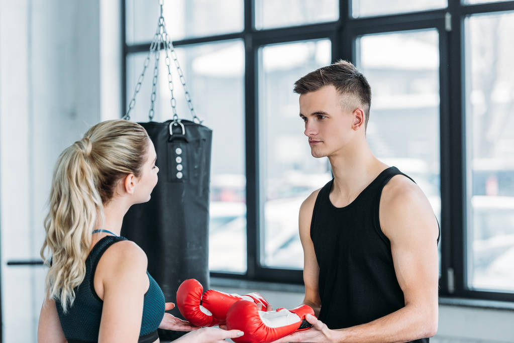 sportif genç kadın spor salonunda boks eldivenleri veren genç erkek eğitmeni - Fotoğraf, Görsel