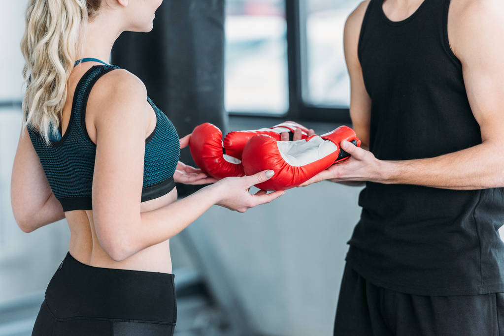 recortado tiro de joven deportivo hombre y mujer sosteniendo guantes de boxeo en el gimnasio
 - Foto, Imagen