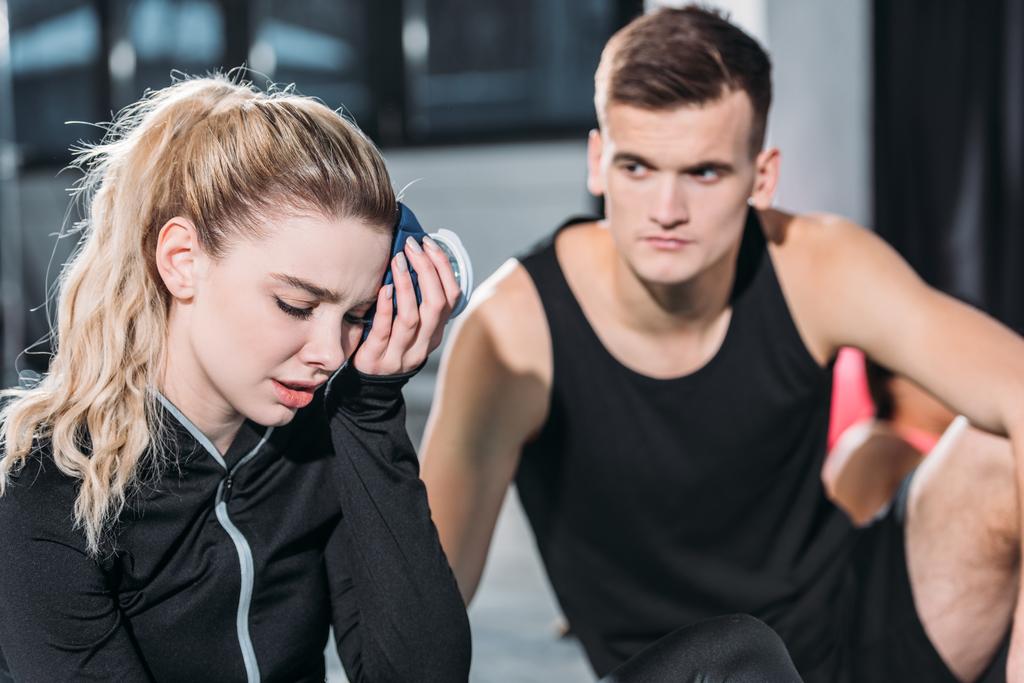 młodego sportowca ogląda zdenerwowany sportowy girl oddanie ice pack do głowy w siłowni - Zdjęcie, obraz