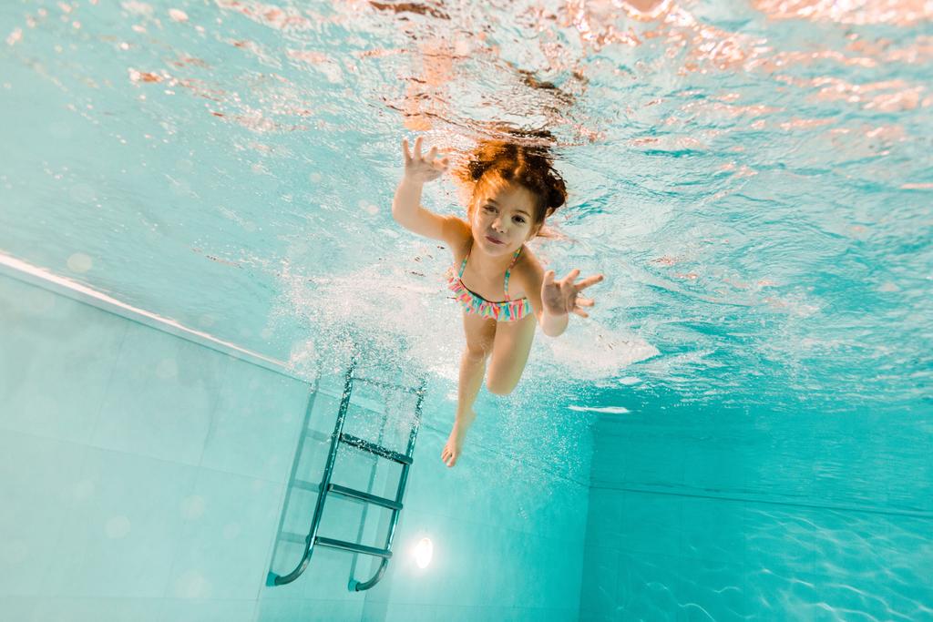 милий хлопець плаває під водою в блакитній воді в басейні
  - Фото, зображення