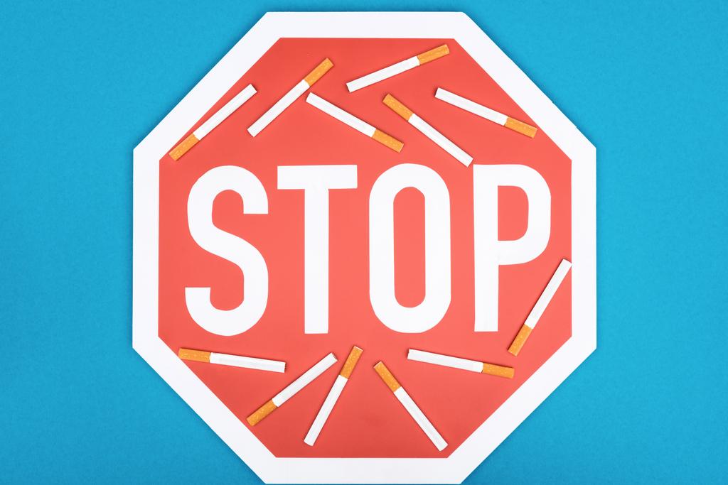 Studio plan de stop signe et cigarettes isolé sur bleu, arrêter de fumer concept
 - Photo, image