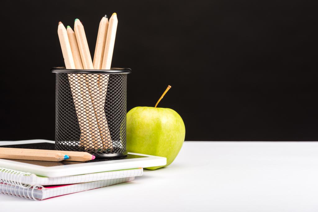 φρέσκο μήλο, τετράδια και μολύβια που απομονώνονται σε μαύρο - Φωτογραφία, εικόνα