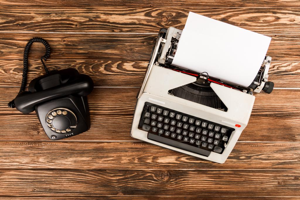 Draufsicht auf Schreibmaschine und Drehwahltelefon auf Holztisch - Foto, Bild