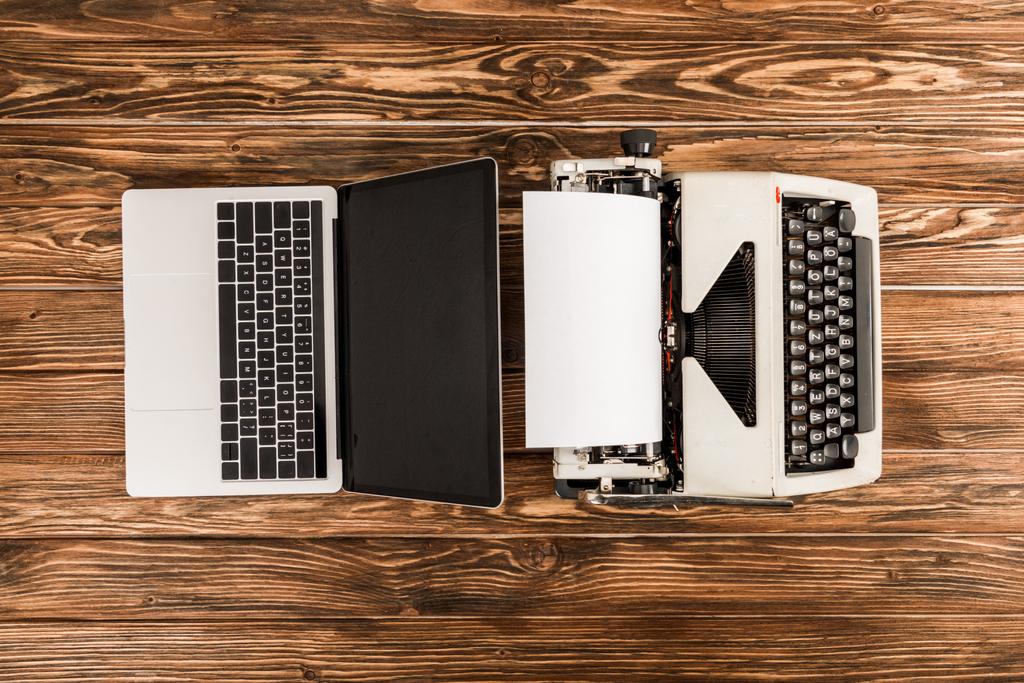 Draufsicht auf Schreibmaschine und Laptop auf Holztisch - Foto, Bild