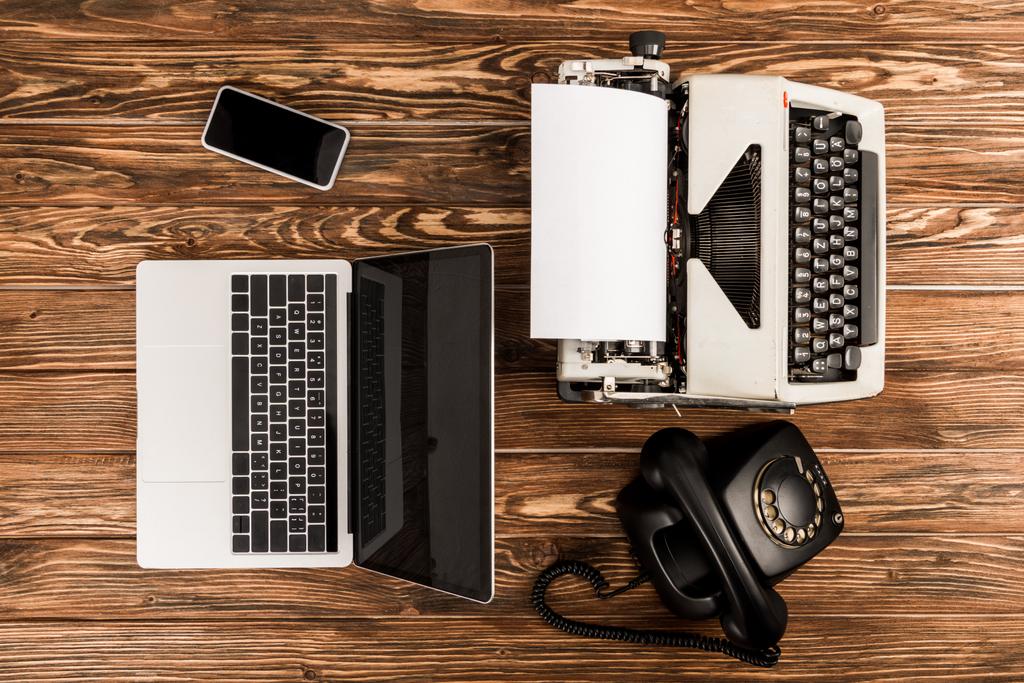 вид пишущей машинки, ноутбука, ротационного телефона и смартфона на деревянном столе
 - Фото, изображение