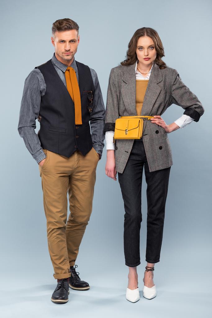 schönes stylisches Paar in formaler Kleidung, das in die Kamera schaut, während es auf grauem Hintergrund posiert - Foto, Bild