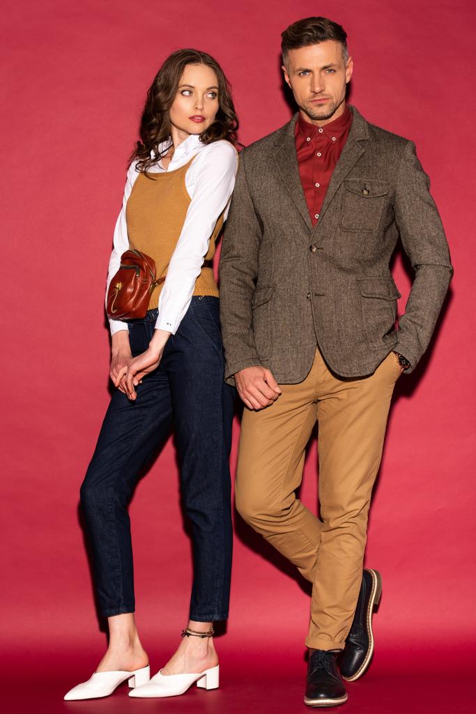 attraente coppia alla moda in abbigliamento formale in posa su sfondo rosso
 - Foto, immagini