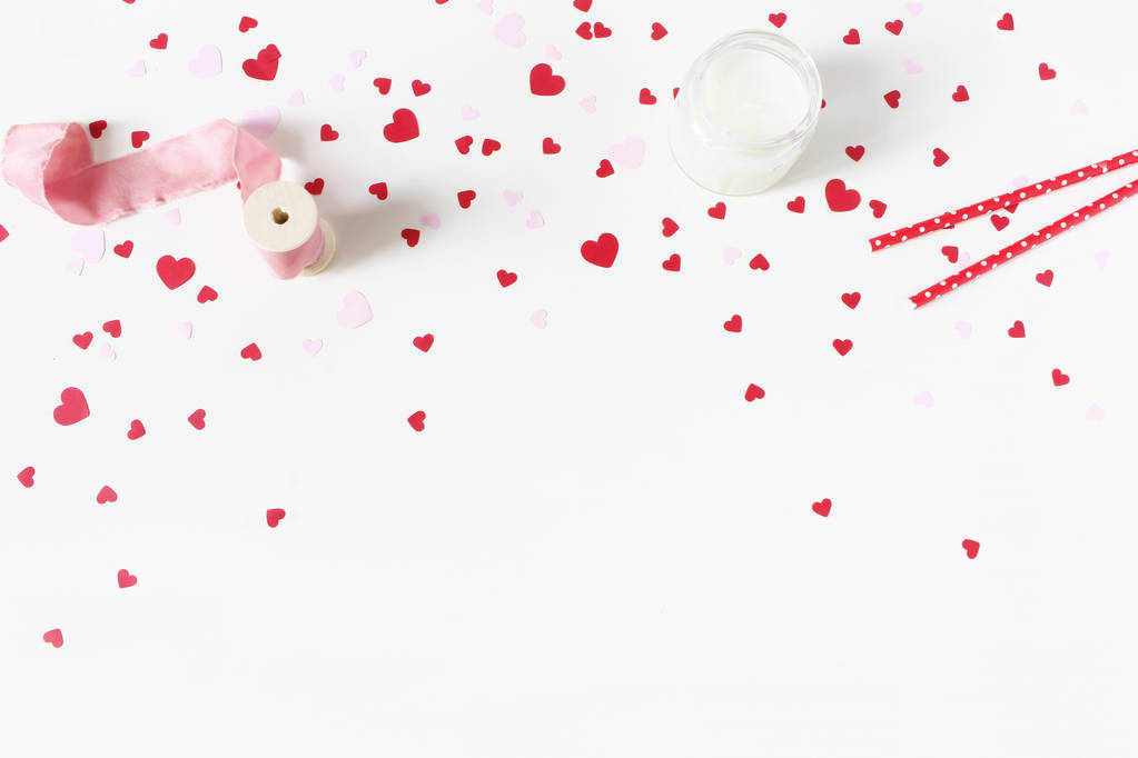 De dag van Valentijnskaarten, bruiloft stilleven scène. Kaars, papier hart confetti, zijde lint en drink rietjes op witte tabelachtergrond. Begrip van de liefde. Plat lag, top uitzicht. - Foto, afbeelding