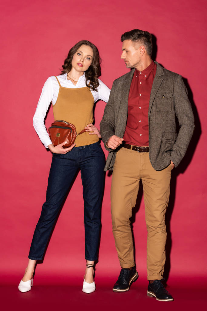 mooie stijlvolle paar in formele slijtage poseren op rode achtergrond - Foto, afbeelding