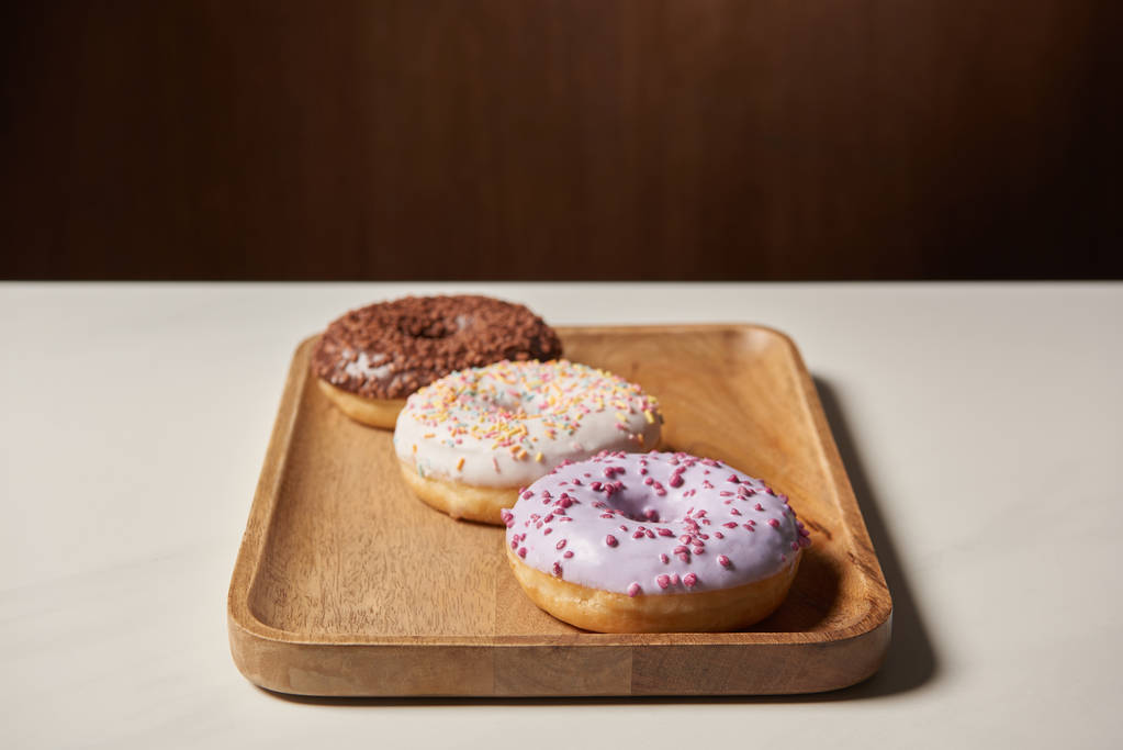 donuts vidrados doces com polvilhas na placa de corte de madeira
 - Foto, Imagem
