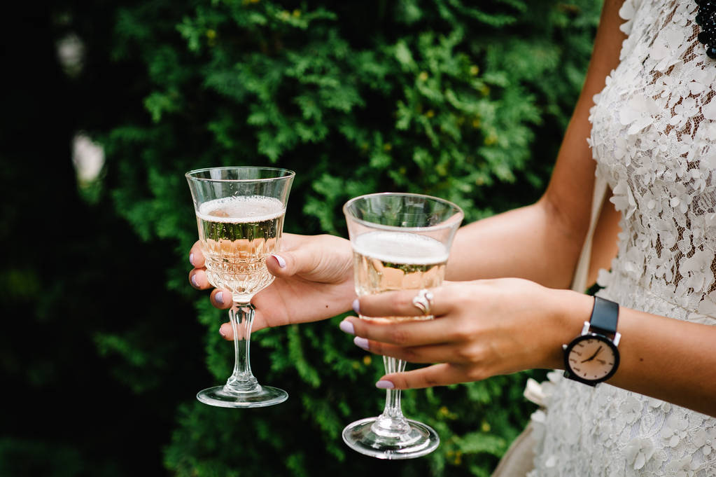 Невеста держит бокалы шампанского на свадебной церемонии
 - Фото, изображение