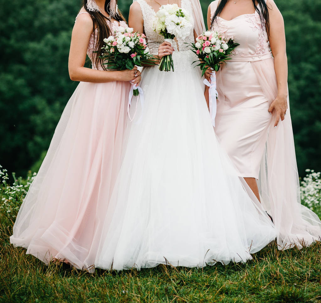 花嫁とブライドメイドのエレガントなドレスに立ってとパステル ピンクの花の花束を保持 - 写真・画像