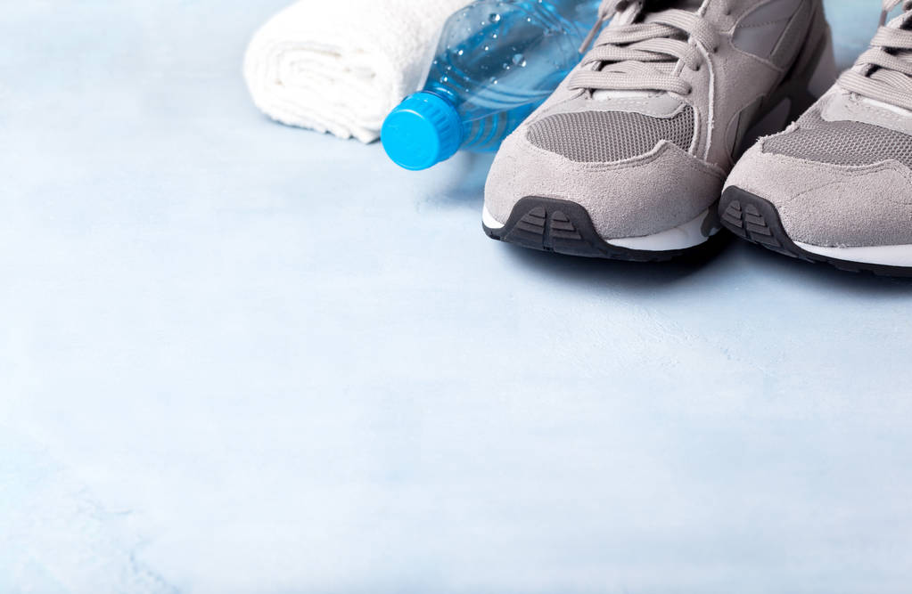 Gri spor ayakkabı, bir şişe su mavi bir arka plan üzerinde.  - Fotoğraf, Görsel