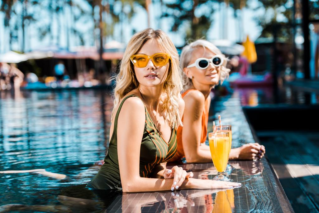 hermosas mujeres pin up relajarse en la piscina con cócteles
 - Foto, Imagen